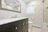Bathroom featuring a dark wood vanity with a white countertop, brushed nickel faucet, large decorative mirror, and tiled flooring