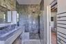 Bathroom featuring a marble finish shower and vanity