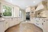White cabinetry with dark hardware, granite countertops, tile backsplash, built-in stainless steel appliances