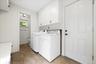 Laundry area featuring wood-finish flooring, white cabinetry, and a white paneled door.