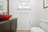 Modern vanity with a red vessel sink, dark countertop, and dark wood-finish cabinet