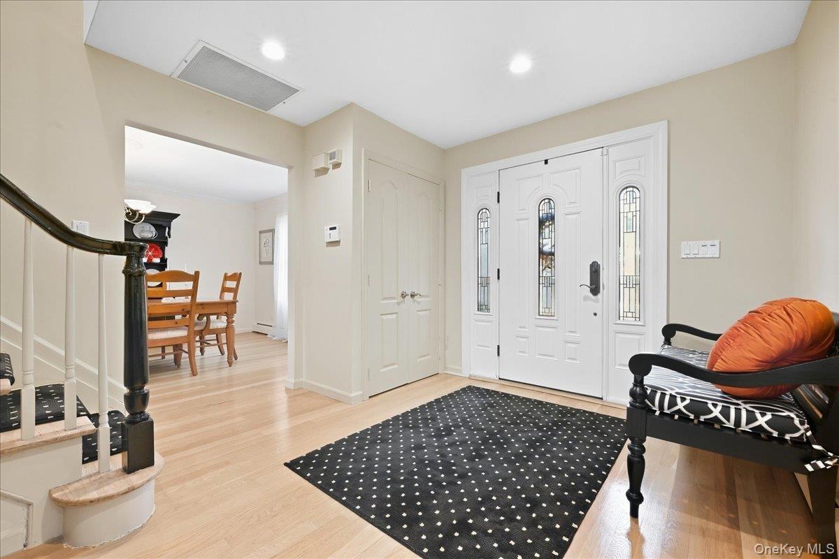 Entryway featuring wood-finish flooring, white paneled doors, and a staircase with a dark wood handrail