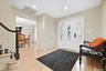 Entryway featuring wood-finish flooring, white paneled doors, and a staircase with a dark wood handrail