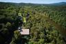 Aerial view of property and surrounding area featuring a forest and a large body of water