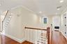 A beautifully crafted staircase featuring hand-drawn detailing, decorative white balusters, and a stunning stained-glass window, showcasing the home's