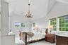 A beautifully appointed oversized bedroom featuring dramatic vaulted ceilings, an elegant chandelier, and expansive windows and en suite bathroom.