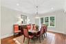 An elegant formal dining room featuring crown molding, rich hardwood floors, a statement chandelier.