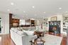 An inviting, open-concept family room anchored by a beautiful fireplace with custom millwork and built-in shelving, seamlessly connecting to the gourm