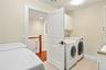 A spacious second-floor laundry room featuring two washers, two dryers, custom cabinetry, and ample storage for added convenience and everyday functio