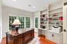 A beautifully appointed private home office featuring custom built-in shelving, integrated file cabinets, dedicated workspace, and expansive windows o