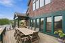An expansive Ipe wood deck featuring generous outdoor dining space, a covered lounge area, and seven glass doors seamlessly connecting the family room