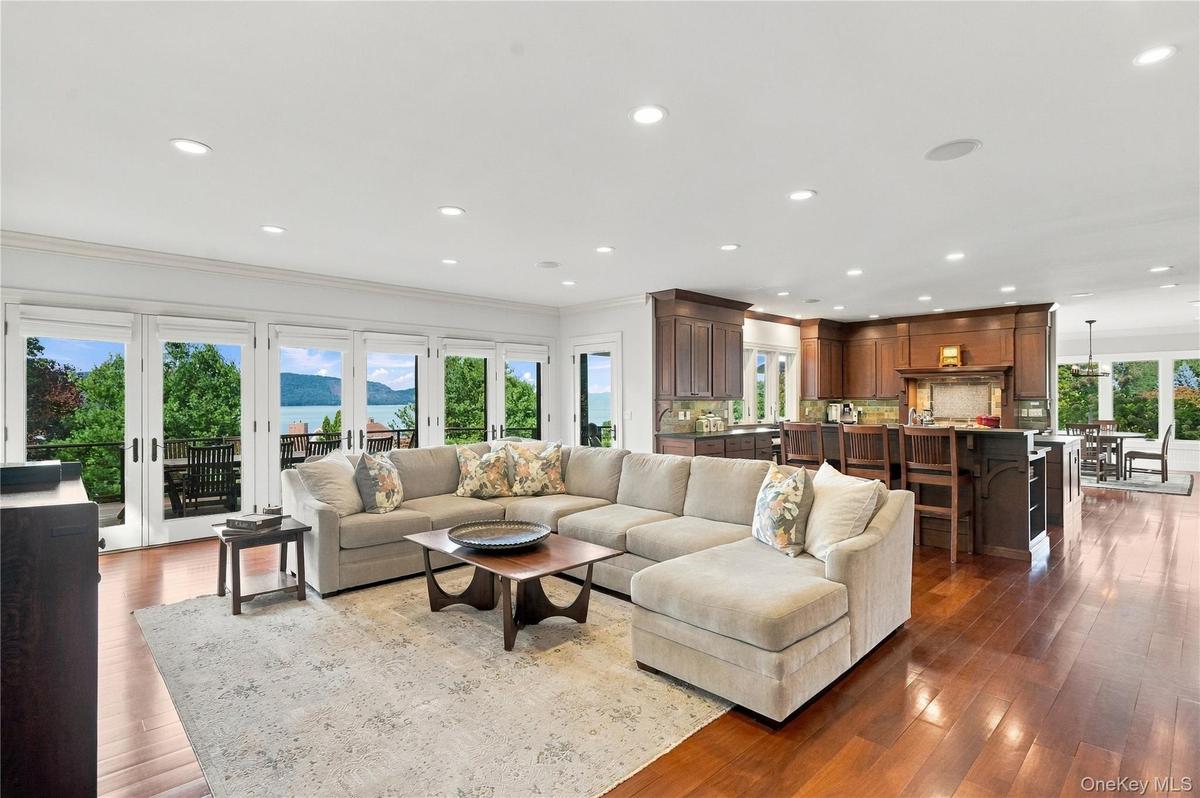 An expansive, open-concept family room and gourmet kitchen featuring custom cherry cabinetry, rich hardwood floors, and walls of glass opening to the 