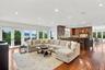An expansive, open-concept family room and gourmet kitchen featuring custom cherry cabinetry, rich hardwood floors, and walls of glass opening to the 