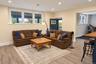 A spacious lower-level living room offering a comfortable setting for relaxation and entertaining, with direct access to the outdoors and adjoining ho