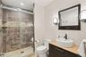 A beautifully finished lower-level bathroom featuring a spacious glass-enclosed shower, custom vanity, and modern fixtures with tasteful custom finish