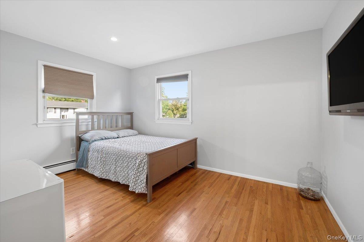 Second bedroom with hardwood floors and recessed lighting.