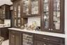 Built-in cabinetry with glass-front uppers, under-cabinet lighting, a patterned tile backsplash, and a beverage refrigerator