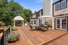 Expansive mahogany-finish deck with pergola  and built-in outdoor kitchen, and French doors providing direct access to the interior