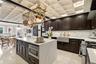 Coffered ceiling with recessed lighting, Farmhouse  stone sink with brass-finish faucet, and a center island with integrated microwave