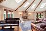 Vaulted ceiling with exposed wood beams, multiple skylights, stone-clad fireplace, and hardwood flooring
