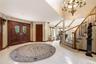 Grand entry with custom carved double doors, marble flooring, a curved staircase with wood balusters.