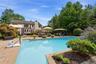 Expansive outdoor living area featuring a large swimming pool with a stone paver surround, a multi-level deck, mature landscaping, and a well-maintain