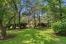 Manicured lawn with mature trees, established shrubbery, and mulched landscaping beds