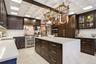 Kitchen featuring a coffered ceiling, black oak  cabinetry, quartz countertops, a large center island, and stainless steel appliances