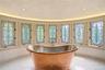 Striking freestanding copper soaking tub, surrounded by stained-glass windows.