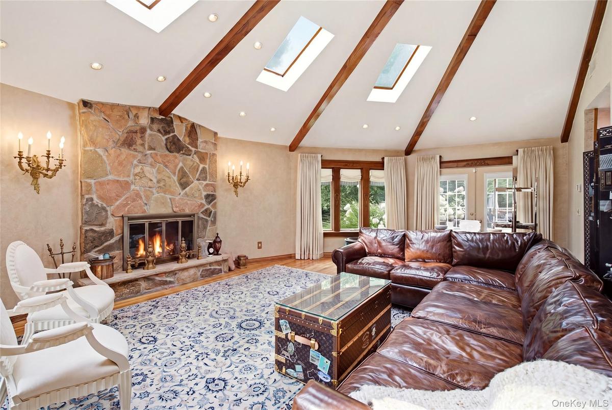 Vaulted ceiling with exposed wood beams,  skylights, recessed lighting, and hardwood flooring