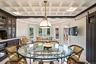 Recessed lighting illuminating a coffered ceiling, with glass-front cabinetry, a glass-top dining table, a white French door, and a dark wood-finish b