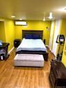 Wood-finish flooring with recessed lighting, an integrated wall-mounted air conditioning unit, and a built-in closet with white panel doors