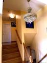 Hardwood stairs with coordinating wood-finish handrails and balusters, featuring a multi-tiered crystal chandelier