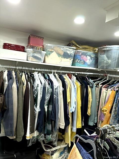 Recessed ceiling lighting illuminating a built-in closet system featuring upper shelving and multiple clothing rods