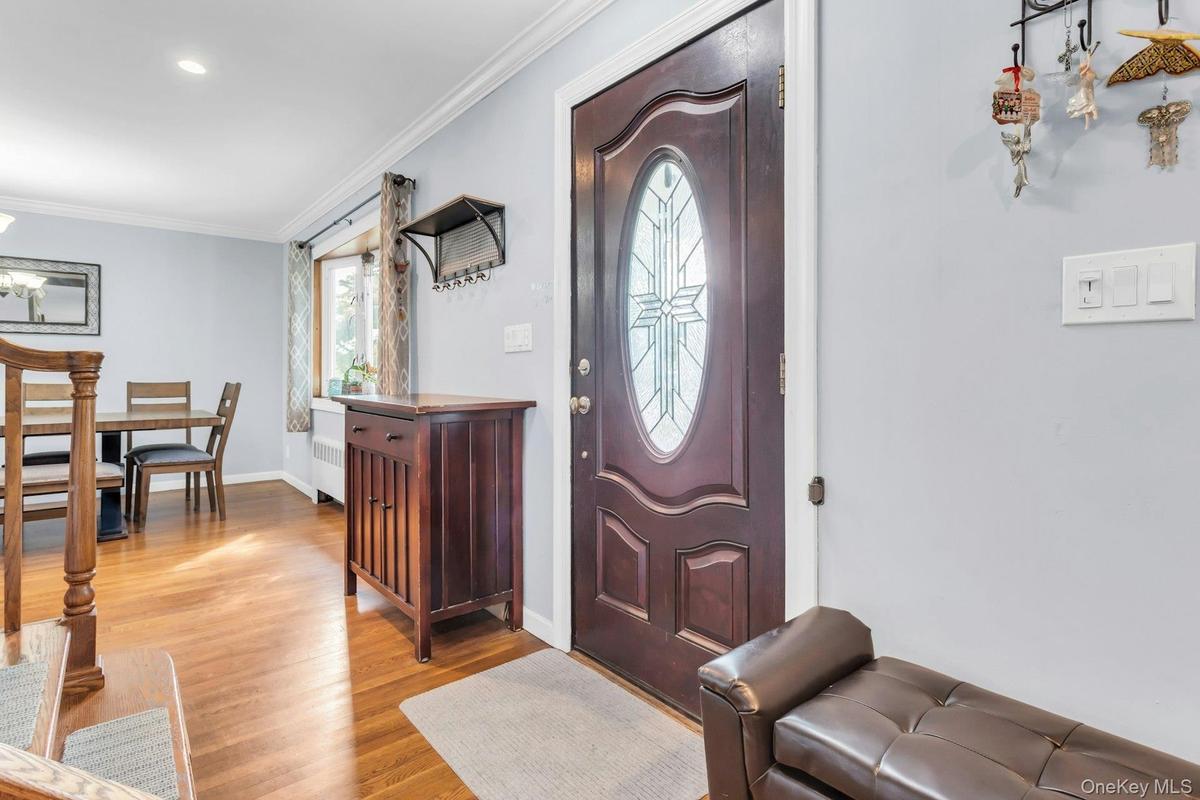 Hardwood flooring, recessed ceiling lighting, crown molding, and a decorative front entry door with an oval glass insert