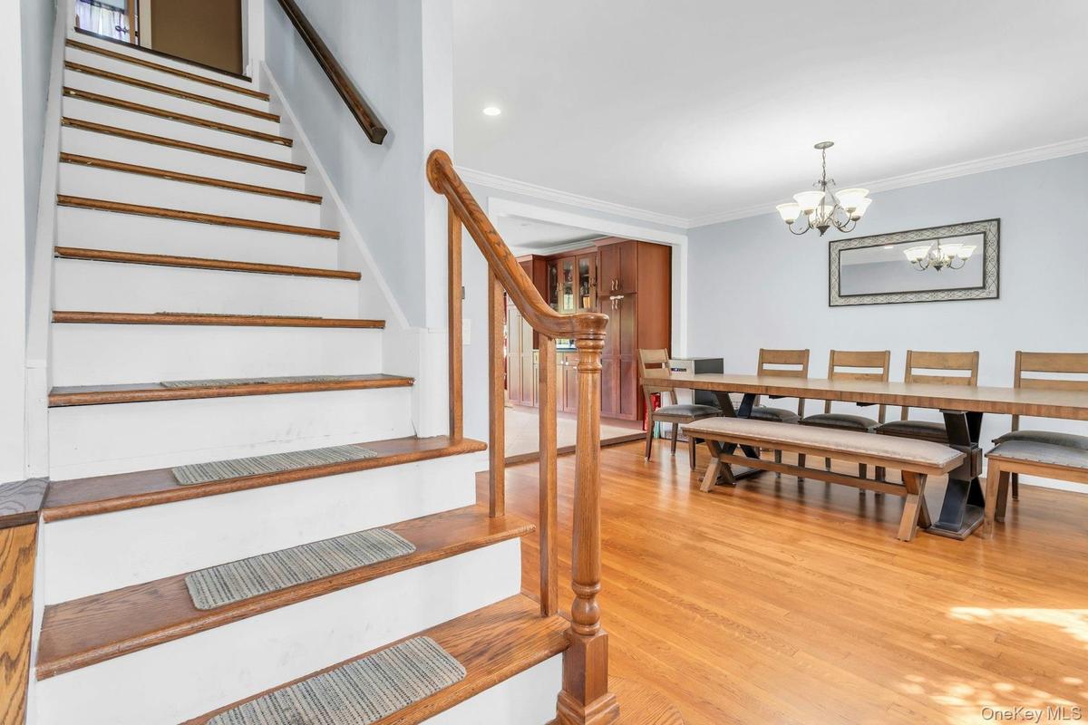Hardwood flooring throughout, crown molding, chandelier lighting, recessed lighting, and a wood staircase with a matching banister