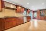 Kitchen featuring wood cabinetry, stainless steel range hood, tile backsplash, black countertops, and recessed lighting