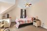Sloped ceiling room featuring a ceiling fan, carpeted flooring, and a single window with curtains