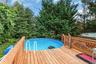 Wood-finish decking surrounding an above-ground swimming pool with integrated entry steps and a lattice-style wood railing