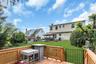 Wood-finish deck with lattice railing, private green lawn, mature perimeter landscaping, and a back patio
