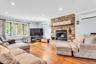 Hardwood flooring throughout, stone-clad fireplace with hearth and wood mantel, large multi-pane window, recessed lighting, and crown molding