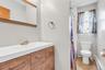 Bathroom featuring a wood-finish vanity with an integrated sink, a framed mirror, and a window with a white frame