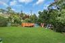 Expansive green lawn featuring a wooden deck, an above-ground pool, and mature perimeter trees