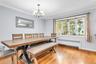 Hardwood flooring throughout, featuring a bay window with a wide sill, crown molding, and an overhead chandelier