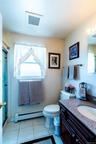 Bathroom featuring a dark wood-finish vanity with an integrated sink and granite-finish countertop, tiled flooring, and a window with natural light