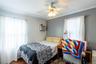 Wood-finish flooring, two windows, crown molding, and a ceiling fan with light fixture