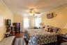 Wood-finish flooring with crown molding, ceiling fan, two windows with blinds, and wall-mounted air conditioning unit
