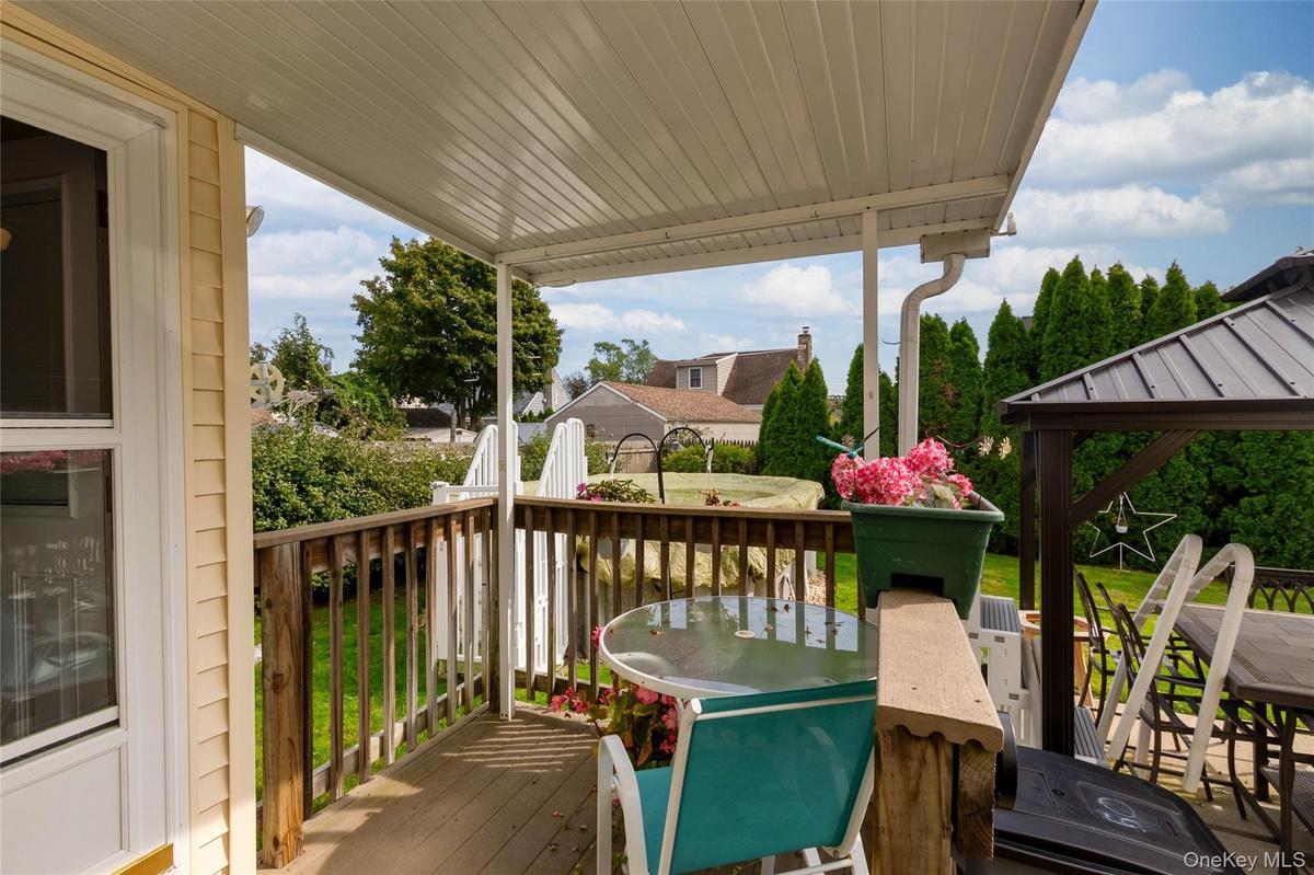Covered wooden deck with a privacy railing and surrounding manicured lawn