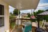 Covered wooden deck with a privacy railing and surrounding manicured lawn