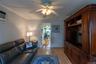 Wood-finish flooring throughout, ceiling fan with integrated lighting, and a built-in wood entertainment center with display shelving
